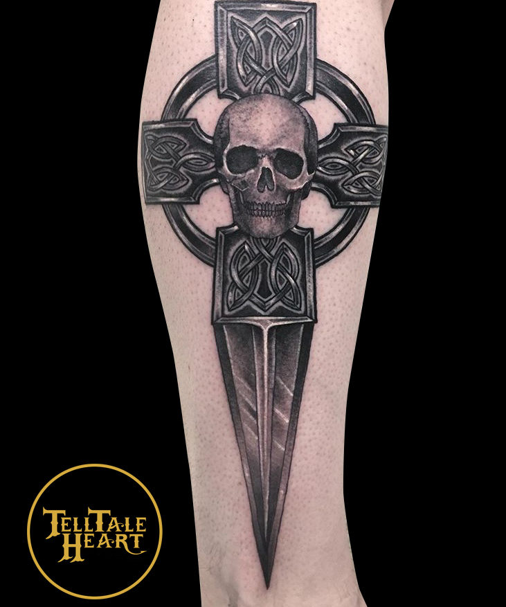 black and grey tattoo of ac celtic dagger with a realistic skull in the middle of the celtic cross tattoed on side of leg