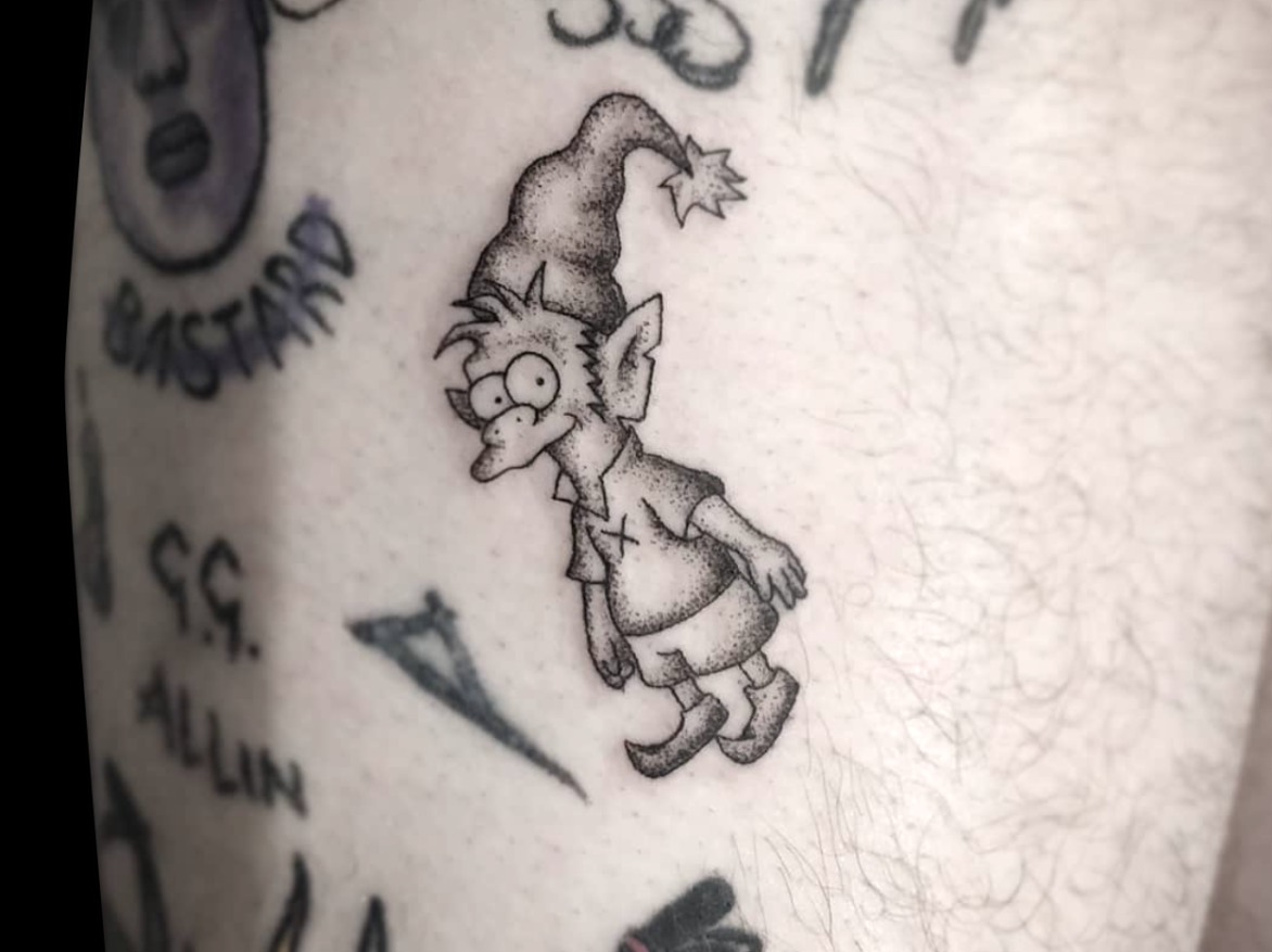 micro tattoo of The Simpsons elf character shaded with dotwork